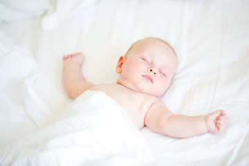 peaceful newborn baby lying on a bed sleeping