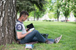 © lexmomot - Group of Teenage Students at Park with Computer and Books