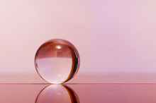Glass Transparent Ball On Light Pink Background And Mirror