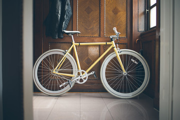 A yellow fixed-gear bicycle (also called fixie)  at home