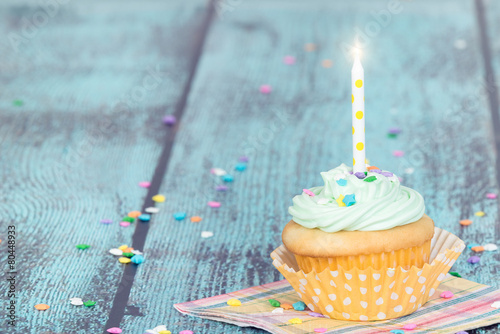 Pastel cupcake with a candle on vintage background Poster