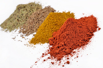 Heaps of different dry spices on a white