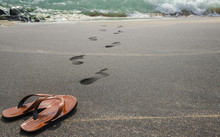 Human Leave His Flip Flops On The Black Sandy Beach And Go To Sw