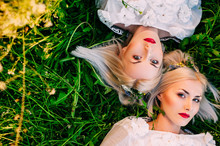 Two Sisters Twins Lying On Green Grass