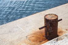 Old Rusted Mooring Bollard On Concrete Pier