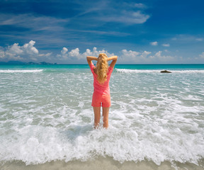 Wall Mural - young woman stretching her arms up on beach against the sky