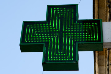 Iluminated Green Pharmaceutical Cross isolated on blue Backgroun