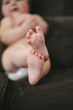 © Mint Images - A baby lying on a sofa, wearing a diaper.