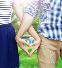 Poster - Loving couple holding hands in shape of heart, close-up