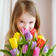 © MNStudio - Adorable little girl holding tulips by the window