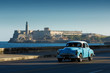 Old classic car on street of Havana with ocean and lighthouse in
