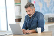 © goodluz - Mature man working on laptop in school office