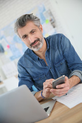 Canvas Print - Teacher using laptop and smartphone in school office