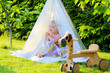 Preschooler girl playing in the garden hiding in tent