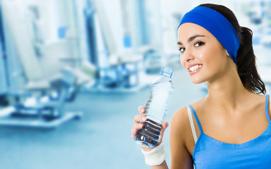 Woman drinking water at gym, with copyspace