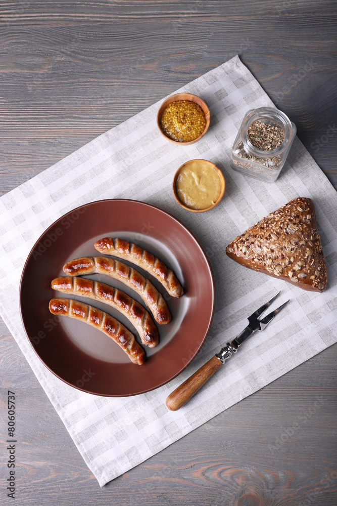 Grilled sausages on plate with bread on table close up