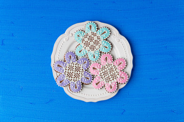 Flowers shaped cookies decorated with ornaments on blue backgrou