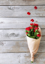 Red Roses Wrapped In Paper On Wooden Table Background