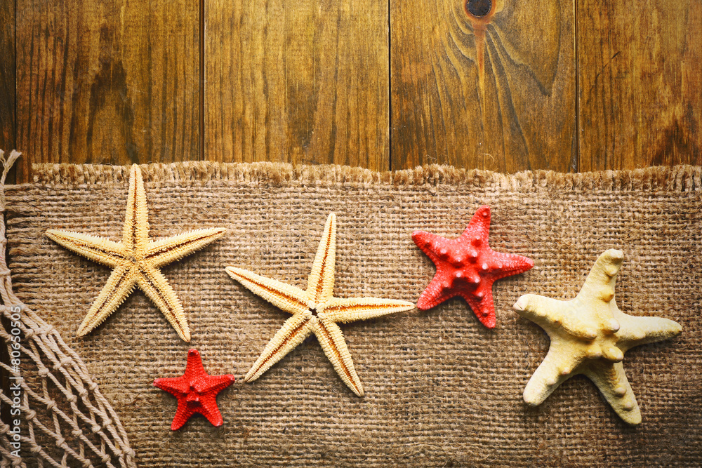 Sea stars on sackcloth on wooden background
