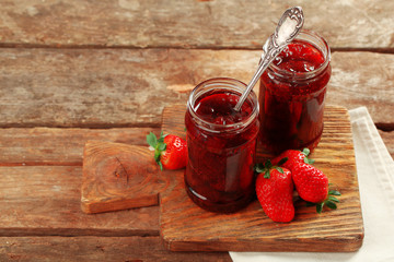 Sticker - Jars of strawberry jam with berries on wooden background