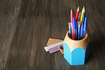 Sticker - Colorful pens and pencils in cup on wooden table background