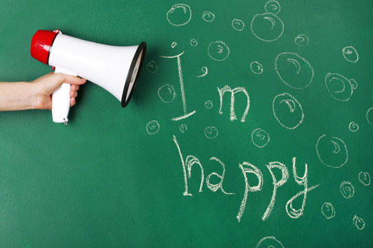 Hand holding megaphone on blackboard background