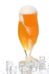 Glass of beer with foam and ice cubes isolated on white