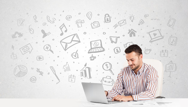 Business man  sitting at table with hand drawn media icons