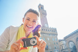 Fototapeta Paryż - Happy young woman with photo camera in front of palazzo vecchio
