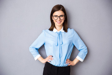 Canvas Print - Smiling businesswoman in glasses over gray background