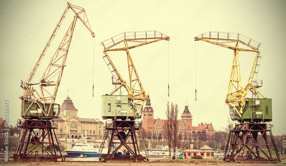Retro stylized picture of port cranes in Szczecin City, Poland. - obrazy, fototapety, plakaty 