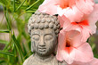 Grey buddha statue in flower garden with bamboo