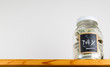 Single glass jar on wooden shelf for saving money