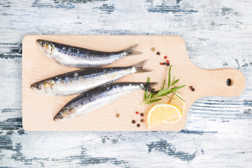 Wall Mural - Fresh anchovy fish on wooden kitchen board.