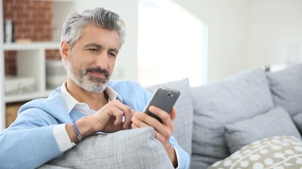 Wall Mural - Mature man sending message with smartphone