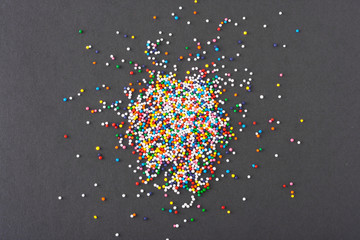 Wall Mural - Colorful round sprinkles spilled on black background, isolated
