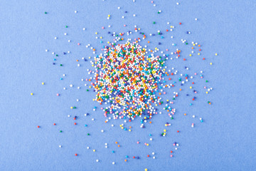 Wall Mural - Colorful round sprinkles spilled on blue background, isolated