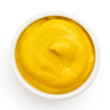 American yellow mustard in round dish from above on white.