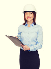 Wall Mural - smiling businesswoman in helmet with clipboard