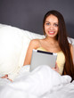 © shefkate - Women use a tablet pc on the bed