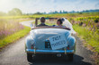 A newlywed couple is driving a retro car, rear view