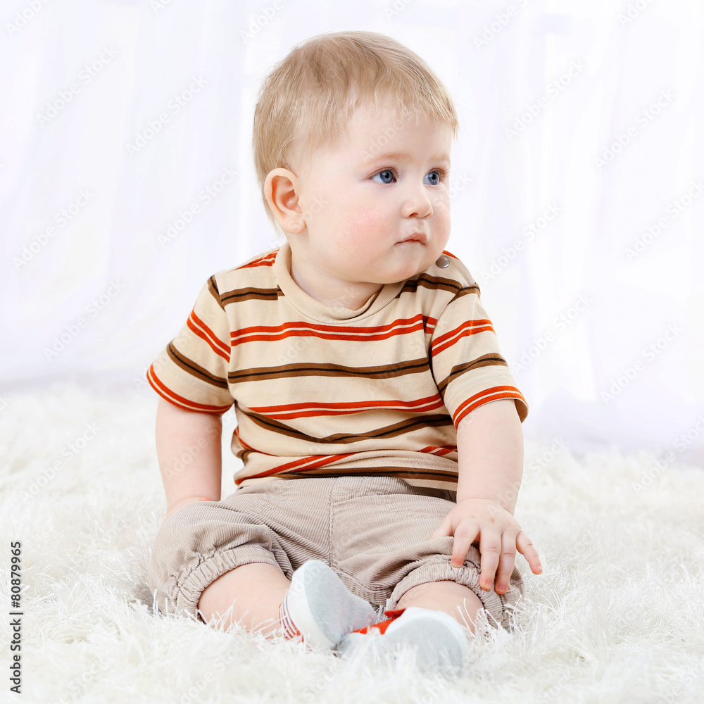 Cute baby boy on carpet, on light background