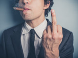 Young businessman with cigar showing rude gesture