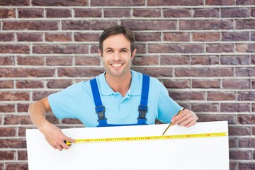 Poster - Composite image of happy carpenter measuring blank bill board