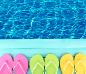 Sticker - Colored flip flops on wooden platform beside sea