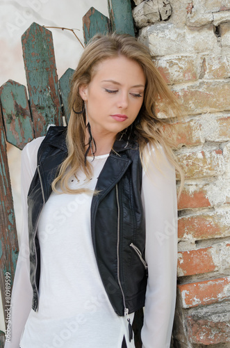 Fotografía Sweet blond woman is leaning against a fence