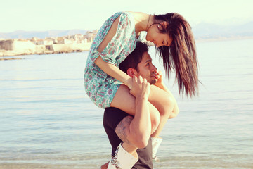 woman sitting on the shoulders of a man near the ocean