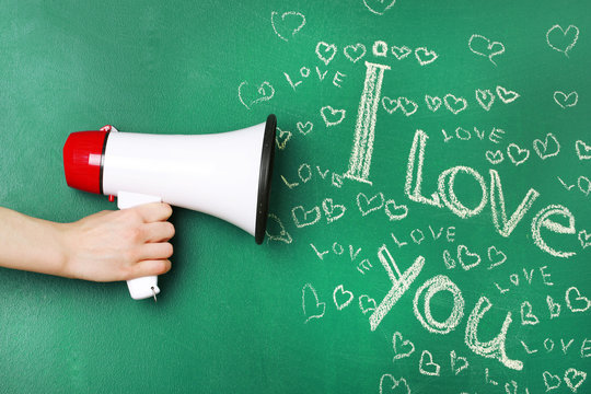 Hand holding megaphone on blackboard background