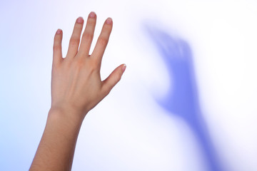 Wall Mural - Female hand and blue shadow on light colorful background