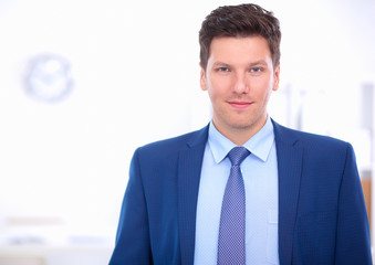 Business man or manager standing against his desk at the office